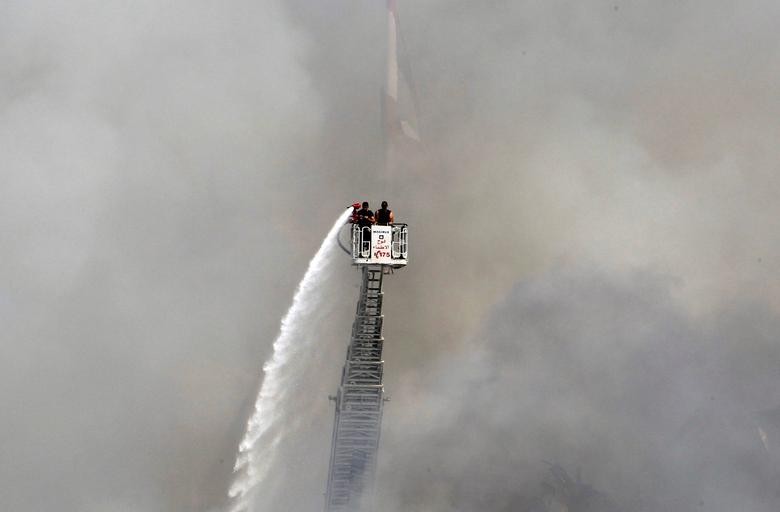 A man uses a water hose to put out the remains of a fire that broke out at Beirut's port yesterday, in Lebanon. REUTERS/Aziz Taher  